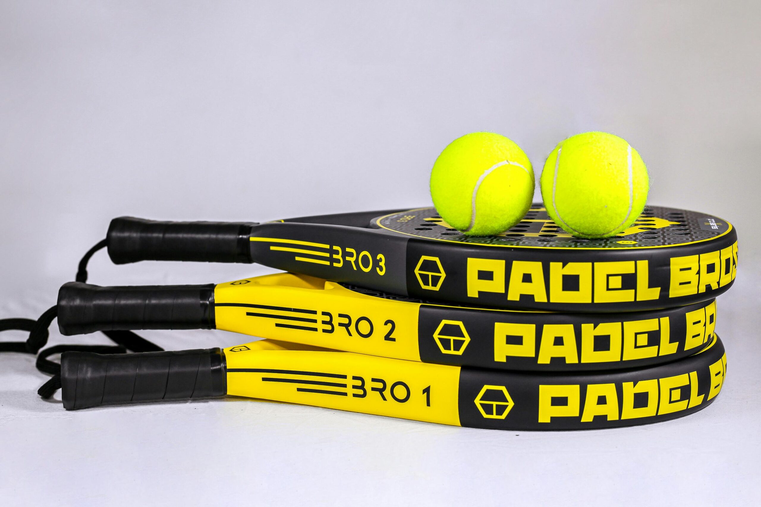 Vibrant padel rackets and tennis balls on white backdrop, ideal for sports themes.